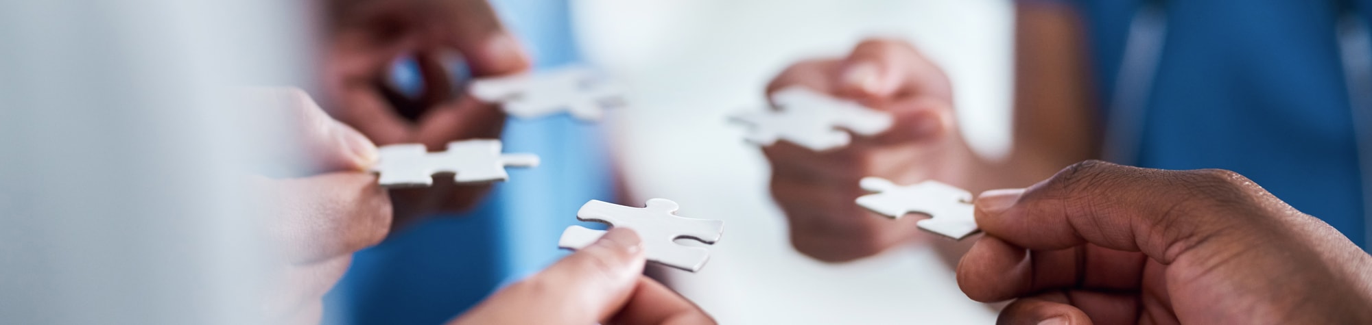 A group of people holding puzzle pieces in a circle