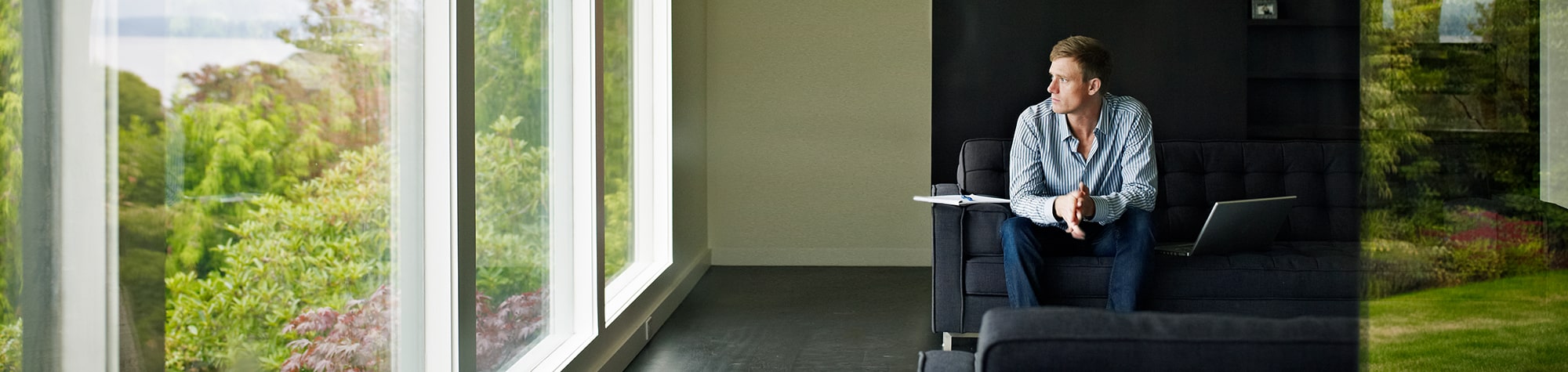 Man sitting down looking out a floor to ceiling glass window
