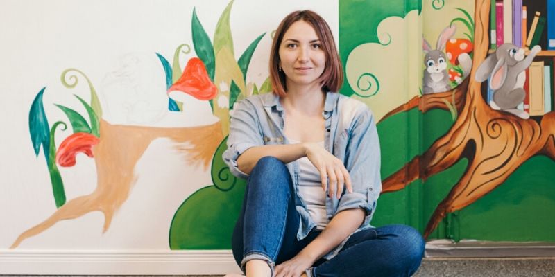 Millennial woman sitting in front of mural
