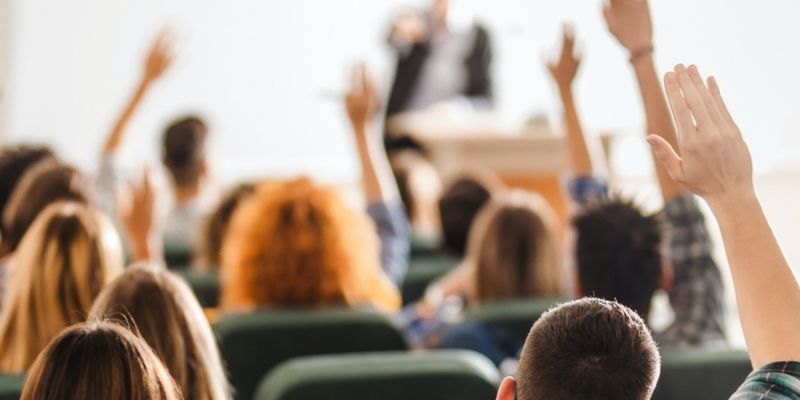 College students raising their hand in a lecture hall