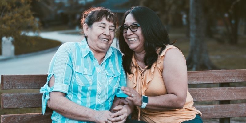 Daughter with her senior mother laughing on a bench